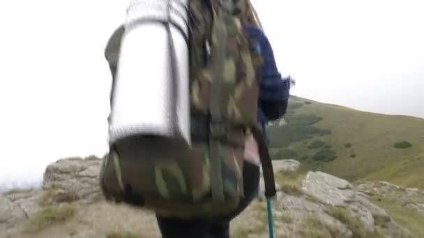 Πεζοπόρος νεαρή γυναίκα με σακίδιο περπάτημα στο βουνό σε πετρώδη πλαγιά φτάνοντας στην κορυφή — Αρχείο Βίντεο