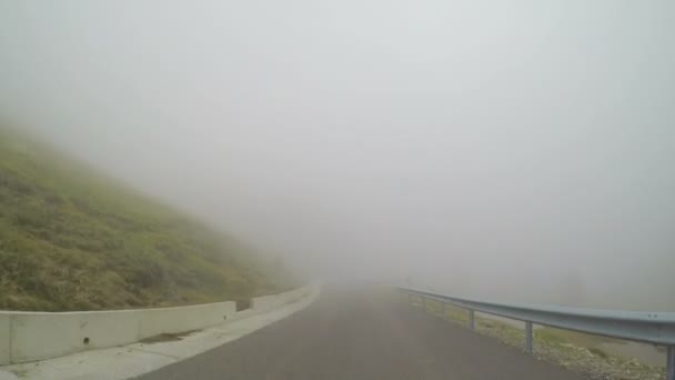 Z pohledu řízení v špatné počasí a špatné viditelnosti díky husté mlze na horské silnici vozidla — Stock video
