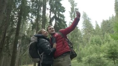 Teknoloji genç çift ormandaki yolculuk deneyimi arkadaşlarınızla paylaşmak görüntülü görüşme için smartphone kullanarak yürüyüşçü tarafından bağlı