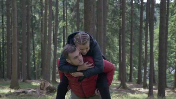 Jonge man die geeft van zijn vriendin een rit van de piggy terug plezier in hun wandeling in het bos — Stockvideo