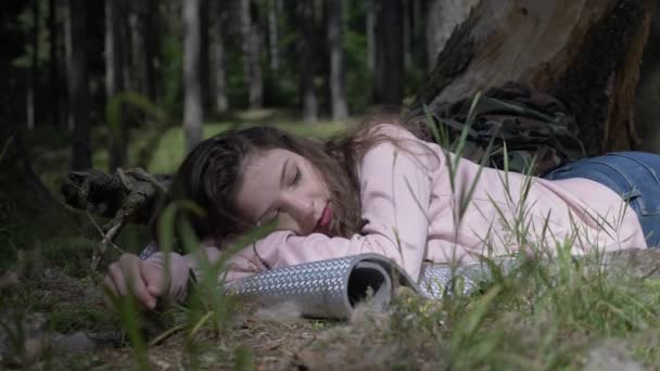 Ocio de la hermosa chica que acampa acostada y relajándose en la hierba en lo profundo del bosque — Vídeo de stock