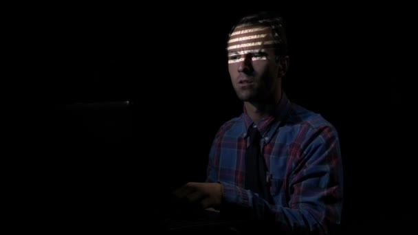 Привабливий чоловічий хакер тримає ручку в роті і успішно ламає блокчейн-сервери зі свого темного схованки — стокове відео