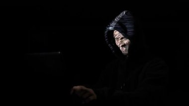 Sabırsız kızgın erkek hacker görüntü yüzünde öngörülen süre dijital labirent veri çatlama karanlık bir odada başlık giyiyor