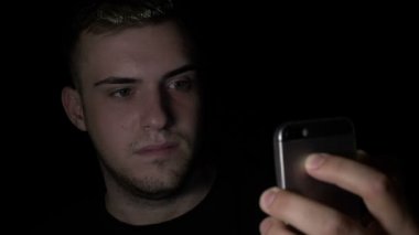 Genç genç erkek yüzü inceden inceye gözden geçirmek ve kilidin açılması için bir smartphone ikili kod uygulaması kullanarak