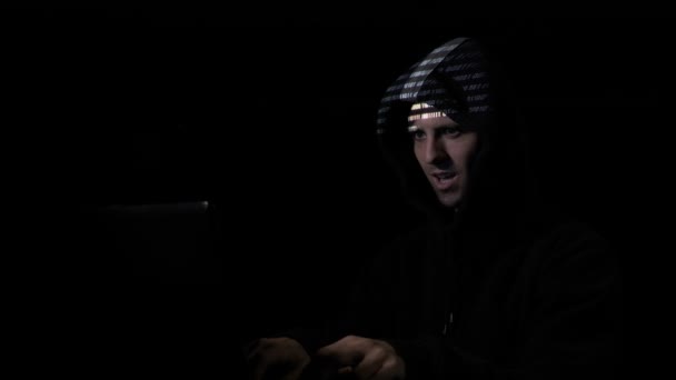 Joven hacker adolescente inconformista organizar ataque de malware a escala mundial, mientras que el código binario se proyecta en su cara — Vídeo de stock