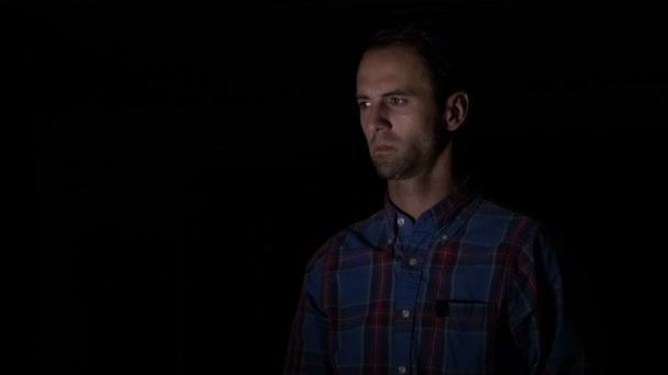 Дорослий чоловік у сорочці, використовуючи розпізнавання обличчя в темній кімнаті, щоб розблокувати свій смартфон — стокове відео