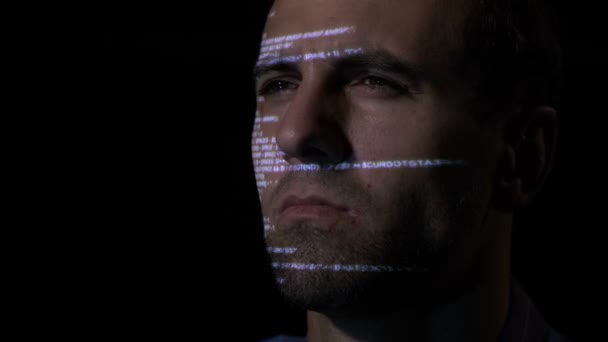Крупный план разработчика программного обеспечения, работающего в темной комнате, пока компьютерный код отражается на его лице — стоковое видео