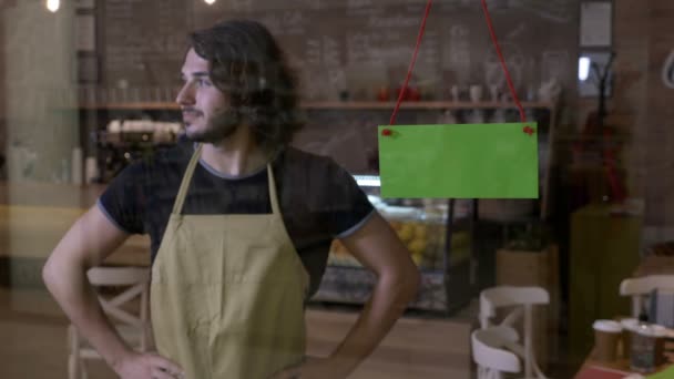 Anxious male server opening coffee shop waiting for clients with hands on hips then rubbing them and flipping over green screen open sign — Stock Video