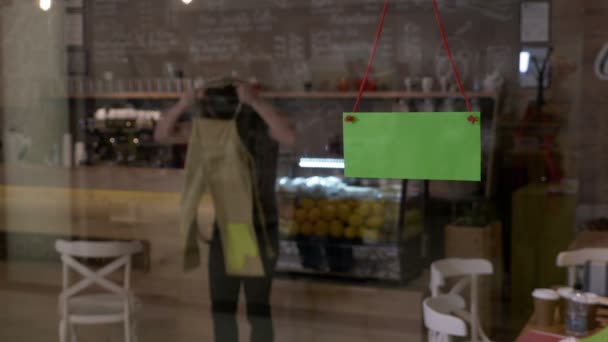 Kis üzlet tulajdonosa, a kávézóban, kezdve a nap a munkahelyen üzembe kötényét és essek zöld képernyő jele az ajtón — Stock videók