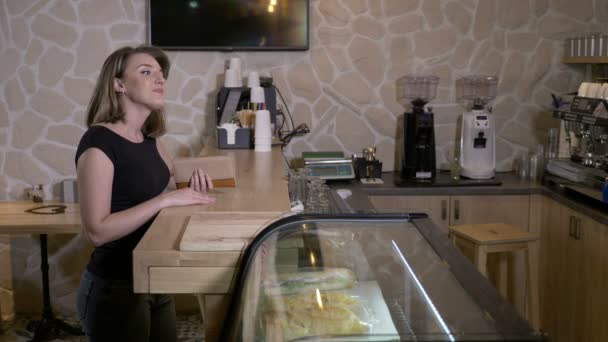 Блондинка привлекательный продавец бариста принимает заказ и подает кофе, чтобы пойти к клиенту, который платит с бесконтактной картой в кафе-магазине — стоковое видео