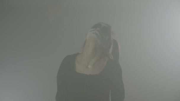 Possessed zombie halloween teenager female with pigtails hair and skull makeup doing robotic movements in smoke — Stock Video
