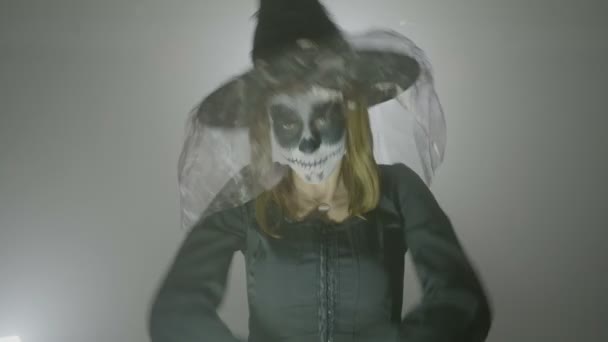 心理女巫与帽子和面纱移动在一个可怕的方式, 并试图邪恶的脸的表情万圣节包围烟雾 — 图库视频影像