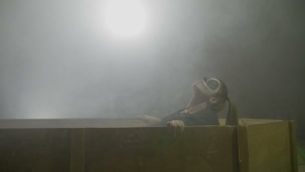 Joven adolescente zombie femenino despertando de entre los muertos saliendo de su ataúd sobre un fondo de humo gris con niebla en la noche de halloween — Vídeo de stock