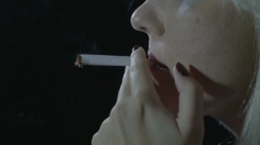 Teneffüs edilmesi ve bulutlar duman exhaling ot sigara yıldırım karanlıkta oturmuş bir depresif sarışın genç kızın yakın çekim