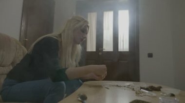 İşten sonra ateş olma sakin evde Esrar sigara haddeleme ve duman güzel sarışın genç kadın