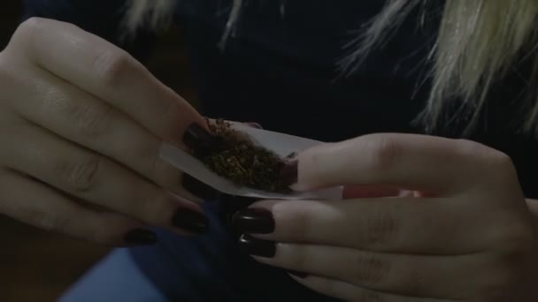 一个女人的手与长指甲纸与烟草制作自己的大麻香烟 — 图库视频影像