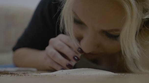 Narcotic attractive female actress snorting cocaine from the table while sitting alone in her apartment — Stock Video