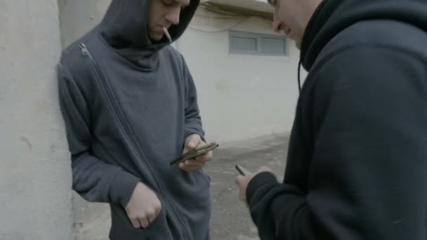 Les voisins masculins se rencontrent devant le bloc pendant la journée pour acheter de la marijuana pour la fête de fin de nuit en échange de paiement Bitcoin crypto-monnaie — Video
