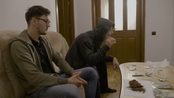 Narkotika student lidi sedící na gauči s tabulkou plné drog blesk jointa marihuany a sdílení uvnitř bytu — Stock video
