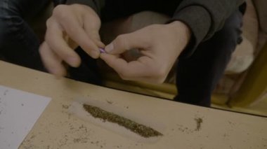 Mükemmel ot ortak filtre haddeleme ve sonra sigara kağıdı sopa için dilini kullanarak bir keş adam elinde yakın çekim