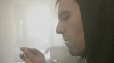 Onun Kiralık Daire içinde kanepede onun arkadaş sigara ot ile kanepede oturan başlıklı bir genç erkek reggae müzisyeni yakın çekim
