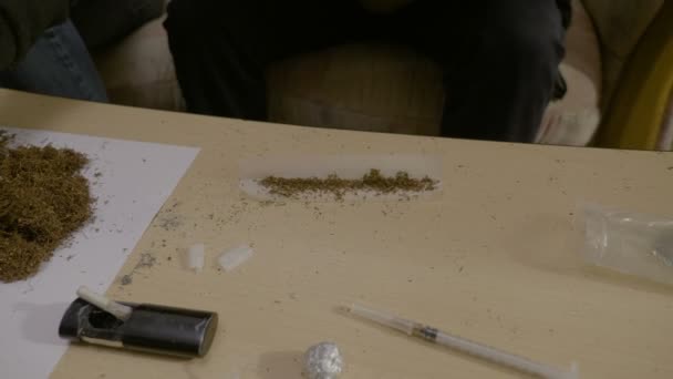 Primer plano de un traficante de drogas masculino que mezcla tabaco con marihuana para crear el porro perfecto para fumar dentro de la casa — Vídeos de Stock