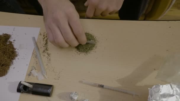 Primer plano de un hombre adicto a la marihuana separando la cantidad de hierba sobre la mesa en cuatro cantidades para las siguientes articulaciones — Vídeos de Stock