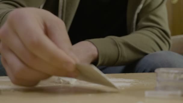 Acercamiento de un joven estudiante consumidor de drogas inhalando cocaína de la mesa de su sala de estar mientras está sentado en el sofá — Vídeo de stock