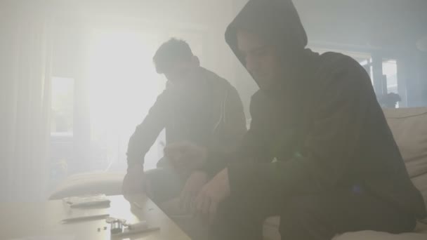 Niños estresados traficantes de drogas fuman marihuana dentro de la casa de la droga en una habitación llena de humo mientras pasan las manos por el cabello — Vídeos de Stock