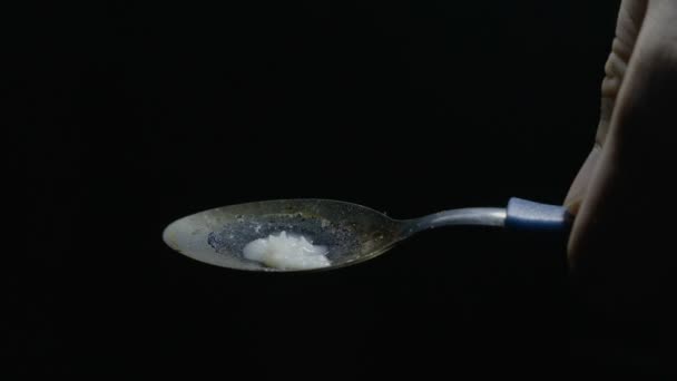 Primo piano di una dose di eroina per il riscaldamento manuale dei consumatori di droga con un cucchiaio e un accendino in una stanza buia — Video Stock
