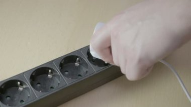 Dalgalanma koruyucusu prizin içine beyaz adaptör şarj cihazı taktıktan ve sonra güç açma bir genç adam el yakın çekim
