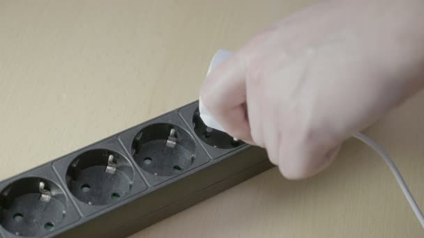 Detailní záběr z rukou mladého muže připojením bílé adaptér nabíječka do prodlužovací Přepěťová ochrana a poté zapnutí napájení — Stock video