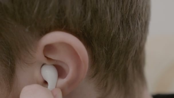 Close up van een jonge jongen oortelefoons aanbrengend zijn oor te luisteren naar muziek en vervolgens weer te verwijderen wegens het hoge volume — Stockvideo