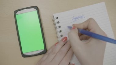 Üstten Görünüm kırmızı kız el ile yeşil ekran smartphone vasıl bakarken onun gündeminde tarifi Malzemeler yazma yemek pişirmeye planlama çivi