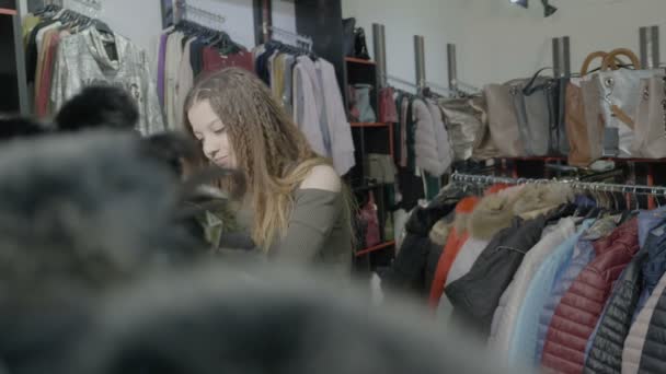 Stijlvolle klant meisje basisstukken van kleding voor haar herfst wintergarderobe kiezen in een mall te slaan — Stockvideo