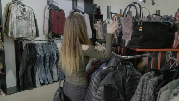 Vackra mysiga kvinnlig student promenader i en butik och letar efter den perfekta väskan att köpa för hennes outfit — Stockvideo