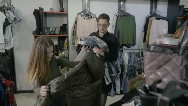 Broer gaat uit naar de winkel met zijn zus en helpt haar de kleren die ze wil proberen op te houden — Stockvideo