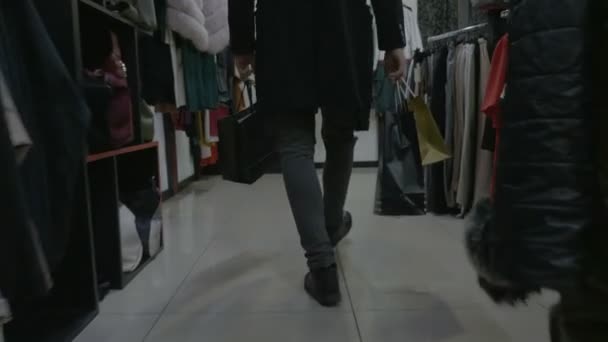 Стрессовый молодой бизнесмен, держащий сумки, заходит в магазин, чтобы успокоиться и ждет свою девушку. — стоковое видео