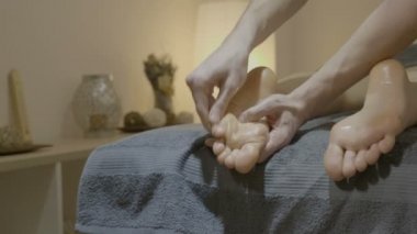 Genç bir erkek terapist bir sağlık merkezinde profesyonel bir masaj almak bir ayak, yakın çekim