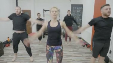 Genç erkekler bir kadın öğretmeni tarafından liderliğindeki bir spor salonu stüdyoda dans ederek ısınma zumba sınıf