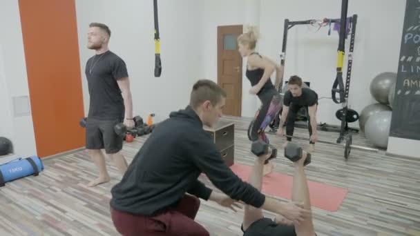 Les jeunes faisant de l'exercice pour perdre du poids au gymnase pendant que l'entraîneur regarde et corrige leur posture de travail — Video