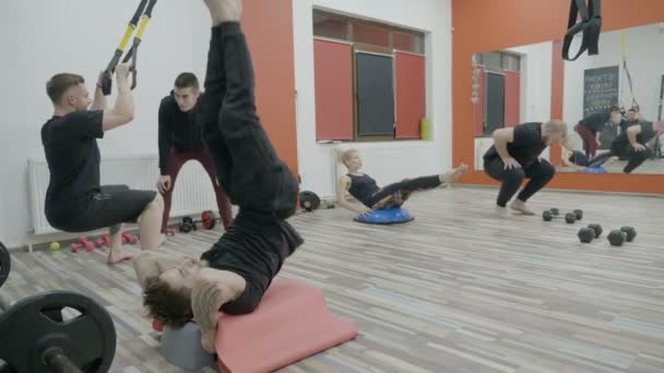 Ung svår couch utbildning motiverande män och kvinnor i ett kors passar gym att hålla sig frisk — Stockvideo