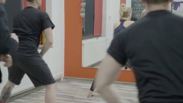 Grup erkek arkadaşıyla birlikte jimnastik salonu kadın bir eğitmen liderliğindeki bir kilo kaybı aerobik sınıf sırasında germe — Stok video