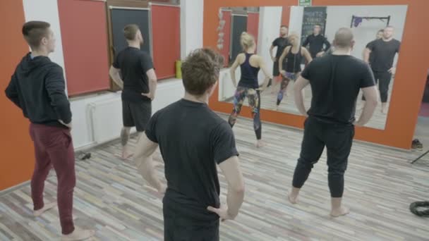 Slanke jonge jongens worming omhoog op de klasse van de dansaerobics op sportschool na de oefeningen van een vrouw fitness instructeur — Stockvideo