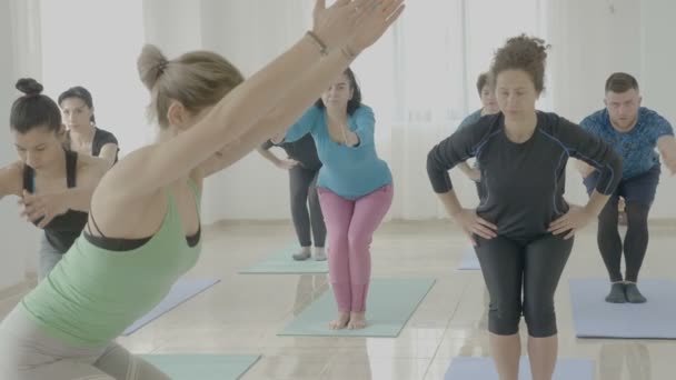 Fuerte atractiva joven instructora de yoga que enseña a las mujeres de mediana edad una nueva pose mientras corrige sus posturas corporales — Vídeos de Stock