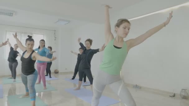 Группа женщин среднего возраста с реальными телами, стоящих на коврике и занимающихся йогой пилатес упражнения в фитнес-студии — стоковое видео