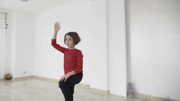 Yavaş bir parlak spor salonu stüdyoda güzel uygun kadın eğitmen küçük bir kız ayakta hala yoga öğretim pozlar — Stok video