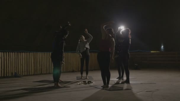 Cours d'aérobic d'étirement dirigé par une femme instructrice dans un endroit froid souterrain sombre éclairé par des lampes — Video