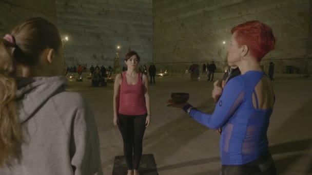 Middle aged women practicing yoga using nepal singing bowl to relax meditate and achieve nirvana in a deep salt mine — Stock Video