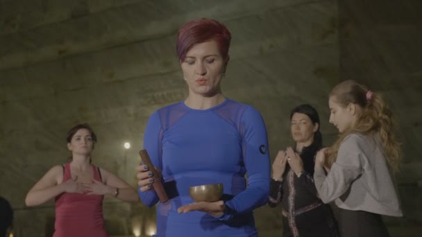 Female nirvana yoga instructor performing a breathing ritual with tibetan singing bowl inside an underground salt mine — Stock Video